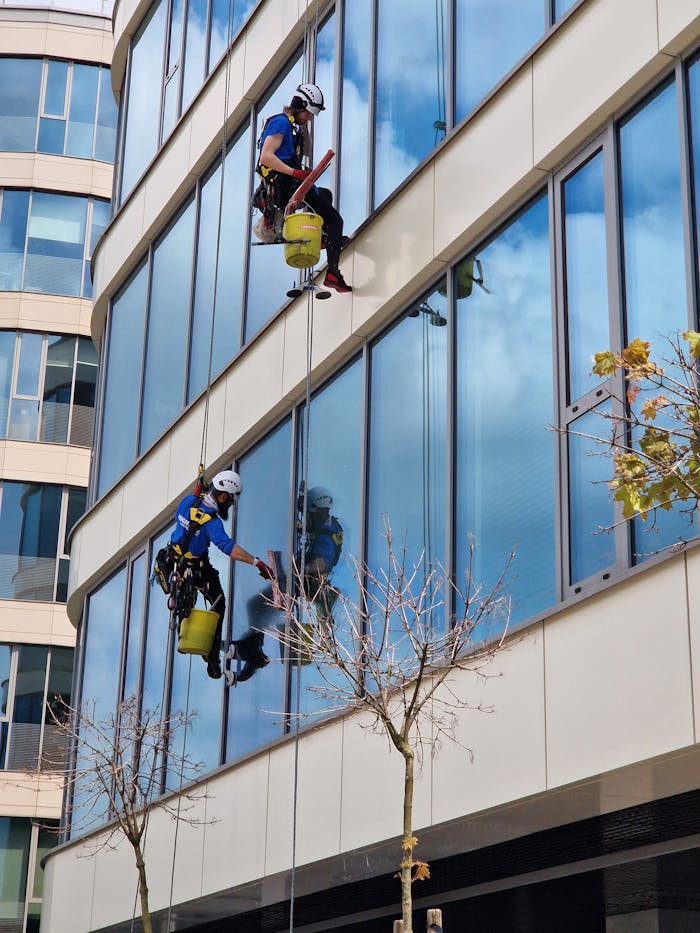 Two window cleaners on a skyscraper, showcasing skill and precision.